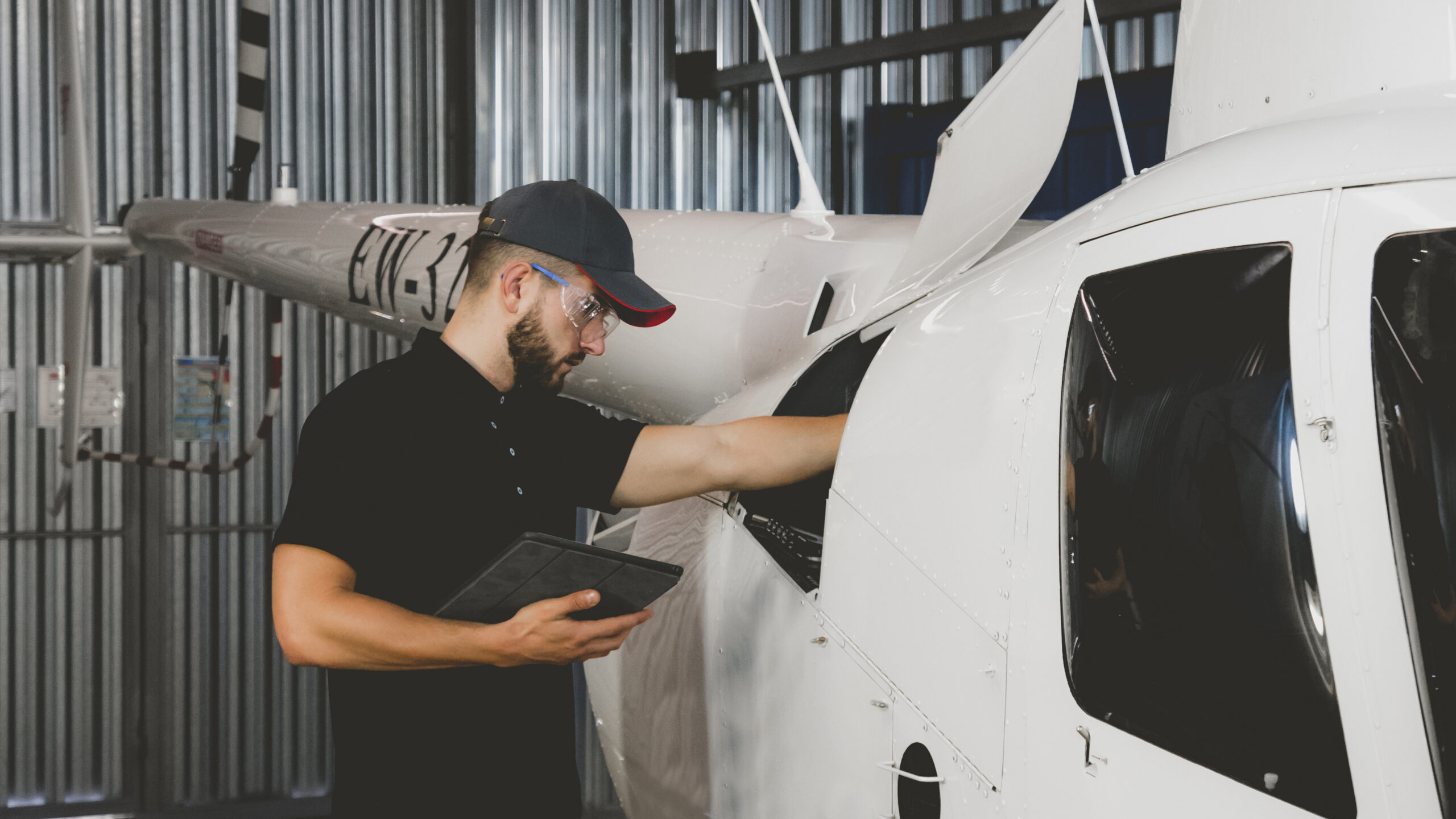 Male mechanic in uniform examining helicopter. Pre flight inspection at the airport